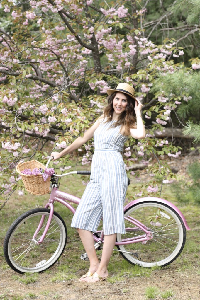 Blue and White Strip Jumpsuit with Boaters Hat with Jack Rogers Hampton Flip Flops on a Pink Cruiser Bike with fresh lilacs