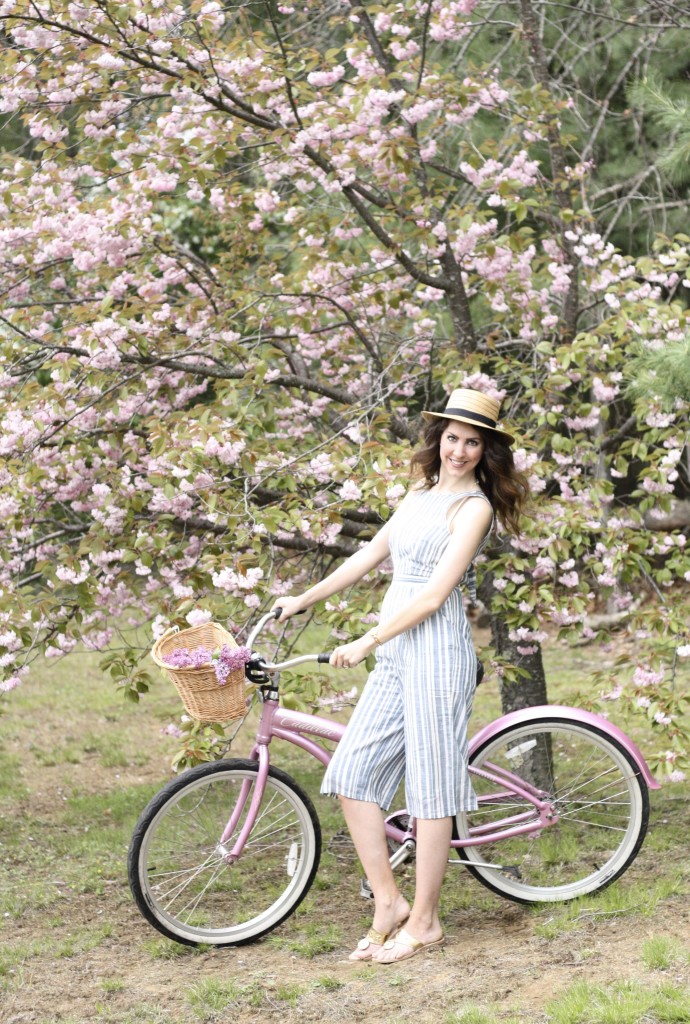 Blue and White Strip Jumpsuit with Boaters Hat with Jack Rogers Hampton Flip Flops on a Pink Cruiser Bike with fresh lilacs