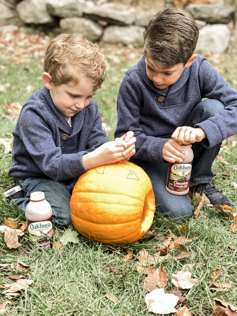 Children in matching fall outfits carving pumpkins Mini Vanilla Spider Web Cupcakes with Oakhurst Dairy Chocolate Milk Halloween Party Recipe