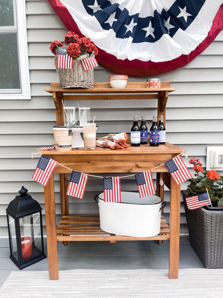 4th of July red white and blue decorated potting table with American flags and root beer floats